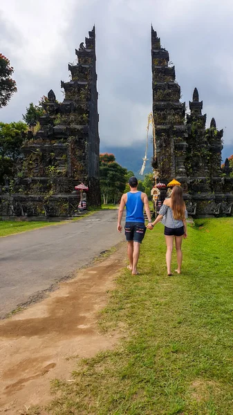 在阴天 一对夫妇站在标志性的巴厘岛汉达拉门前面 周围乌云密布 传统的印度教之门通往黄金之路Handara门四周环绕着茂盛的青山 — 图库照片