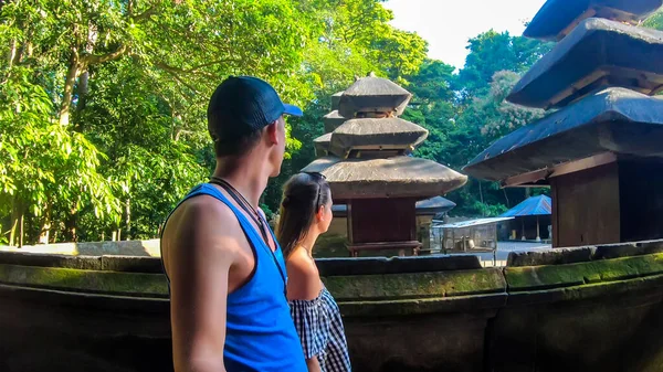 一对夫妇在印度尼西亚巴厘岛的猴林散步 他们正走过一个寺庙建筑群 寺庙四周是竹林 野生和未开垦的地方 与自然和谐相处 — 图库照片
