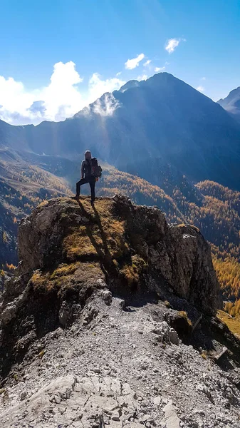 Man with hiking backpack standing on the boulder, while walking to the Grosse Gamswiesenspitze, Lienz Dolomites, Austria. Solo wandering in Alps. Admiring beauty of the nature. Adventure and freedom