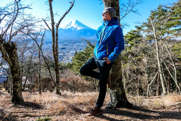 A man standing in a forest on the hilltop above Chureito Pagoda, Japan with Mt Fuji in the back. He is having a lot of fun, enjoying beautiful landscape. Holly mountain in Japan. Clear and sunny day