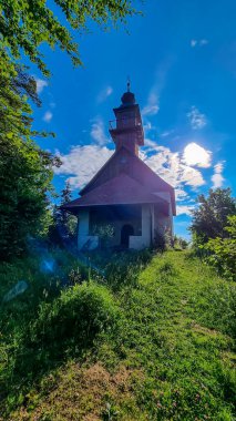 The pilgrimage church on the top of Oswaldiberg near Villach, Carinthia, Austria. The small chapel is surrounded by a dense and bright green forest. Light beams are entering the frame. Serenity clipart