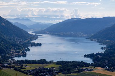 A view on the Lake Ossiach located in the heart of the Alps in Carinthia, Austria. The surface of the lake reflects golden sunbeams. The view is from a chapel on the hilltop of Oswaldiberg. clipart