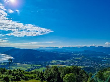 Avusturya, Carinthia 'daki Alplerin kalbinde bulunan Ossiach Gölü manzarası. Gölün yüzeyi altın güneş ışınlarını yansıtır. Manzara Oswaldiberg 'in tepesindeki bir şapelden..