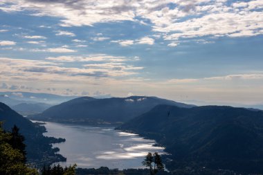 Avusturya, Carinthia 'daki Alplerin kalbinde bulunan Ossiach Gölü manzarası. Gölün yüzeyi altın güneş ışınlarını yansıtır. Manzara Oswaldiberg 'in tepesindeki bir şapelden..