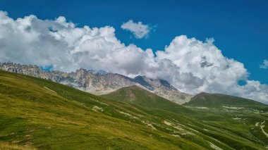 Gürcistan 'daki yüksek Kafkasya dağlarında panoramik bir manzara. Arkada yüksek, karlı tepeler var. Önünde yemyeşil bir çayır var. Idyllic manzara. Sakinlik ve meditasyon. Doğal tedavi.