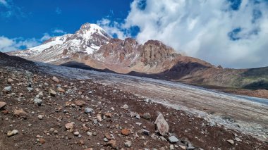 Kafkasya, Georgia 'daki Kazbeg Dağı' nın bulutsuz manzarası. Orada kar kaplı tepenin ve Gergeti Buzulu 'nun altında çorak ve taşlı yamaçlar var. Sükunet. Doğal bir ilaç. Devasa buzul ayağı.