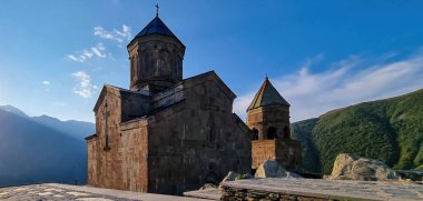 Gürcistan, Stepansminda 'daki Gergeti Trinity Kilisesi' ne yakından bakın. Kilise yüksek bir Kafkas dağında yer almaktadır. Kilisenin üstündeki açık ve mavi gökyüzü. Arkada yüksek dağ zincirleri var..