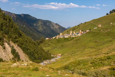 Gürcistan 'ın Svaneti Bölgesi' nin Yüksek Kafkasya bölgesinde yer alan bir dağ köyü olan Adishi 'nin panoramik manzarası. Svan gözetleme kuleleri görülebilir. Bir yürüyüş yolu ve bir nehir köye gidiyor. Yalnızlık