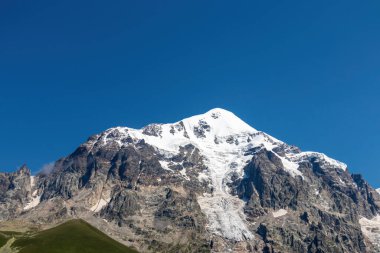Gürcistan, Svaneti Bölgesi 'ndeki Büyük Kafkasya Dağları' ndaki Tetnuldi 'nin karlı zirvesine panoramik bir manzara. Bir buzul dağ yamacından aşağı iniyor. Keskin tepeler, seyahat tutkusu, yalnızlık..