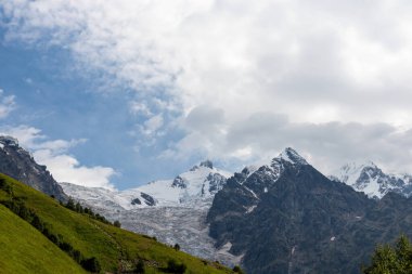 Gürcistan 'ın Büyük Kafkasya Dağları' ndaki Tetnuldi, Gistola ve Lakutsia 'nın karlı zirvelerine panoramik bir manzara. Çayırları yemyeşil tepeler, keskin tepeler, yürüyüş titreşimleri....