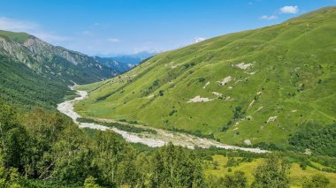 Adishischala Nehri, Georgia, Svaneti Bölgesi 'ndeki Büyük Kafkasya Dağları' ndaki bir vadiden aşağı akıyor. Arkada karla kaplı dağlar var. Vahşi yaşam, uzak konum, yalnızlık..