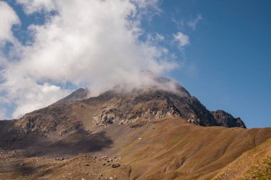 Gürcistan, Kazbegi Bölgesi 'ndeki Büyük Kafkasya Dağları' ndaki Chaukhi topluluğunun keskin dağ zirvelerine panoramik bir manzara. Chaukhi Geçidi 'nden bulutlar yükseliyor. Gürcü Dolomitler. Koşun!