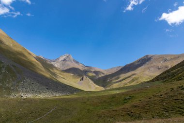 A panoramic view on the green hills and sharp ridges of the mountain peaks of the Chaukhi massif in the Greater Caucasus Mountain Range in Georgia, Kazbegi Region. Wanderlust. Clear Sky. Hike clipart