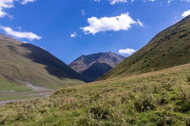 Gürcistan, Kazbegi Bölgesi 'ndeki Büyük Kafkasya Dağları' ndaki Chaukhi topluluğunun yüksek dağ zirvelerinde panoramik bir manzara. Yeşil yemyeşil otlakları olan bir vadi. Seyahat tutkusu. Uzak konum.