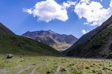 Gürcistan, Kazbegi Bölgesi 'ndeki Büyük Kafkasya Dağları' ndaki Chaukhi topluluğunun yüksek dağ zirvelerinde panoramik bir manzara. Yeşil yemyeşil otlakları olan bir vadi. Seyahat tutkusu. Uzak konum.