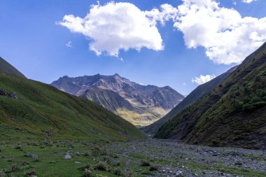 Gürcistan, Kazbegi Bölgesi 'ndeki Büyük Kafkasya Dağları' ndaki Chaukhi topluluğunun yüksek dağ zirvelerinde panoramik bir manzara. Yeşil yemyeşil otlakları olan bir vadi. Seyahat tutkusu. Uzak konum.