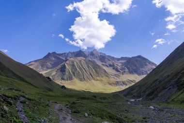 Gürcistan, Kazbegi Bölgesi 'ndeki Büyük Kafkasya Dağları' ndaki Chaukhi topluluğunun yüksek dağ zirvelerinde panoramik bir manzara. Yeşil yemyeşil otlakları olan bir vadi. Seyahat tutkusu. Uzak konum.