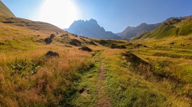 Gürcistan, Kazbegi Bölgesi 'ndeki Büyük Kafkasya Dağları' ndaki Chaukhi topluluğunun keskin dağ zirvelerine panoramik bir manzara. Yeşil bir çayırda yürüyüş parkuru. Gürcü Dolomitler.