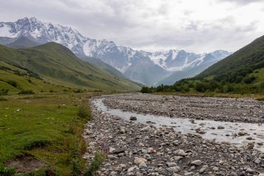 Patara Enguri Nehri, Ushguli 'nin Svaneti Bölgesi, Gürcistan' daki Büyük Kafkasya Dağları 'ndaki Shkhara Buzulu' nu gören bir vadiden aşağı akar. Arkada karla kaplı dağlar var. Vahşi doğa