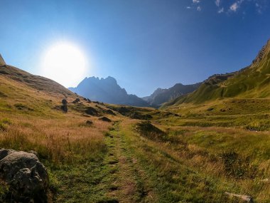 Gürcistan, Kazbegi Bölgesi 'ndeki Büyük Kafkasya Dağları' ndaki Chaukhi topluluğunun keskin dağ zirvelerine panoramik bir manzara. Yeşil bir çayırda yürüyüş parkuru. Gürcü Dolomitler.