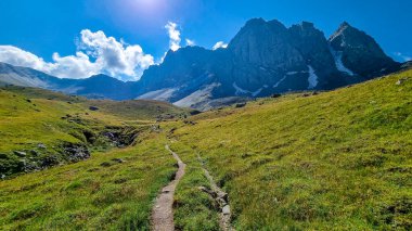 Gürcistan, Kazbegi Bölgesi 'ndeki Büyük Kafkasya Dağları' ndaki Chaukhi topluluğunun keskin dağ zirvelerine panoramik bir manzara. Yeşil bir çayırda yürüyüş parkuru. Gürcü Dolomitler.