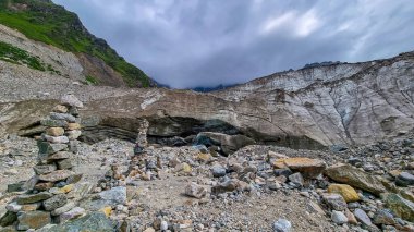 Stacked stones in front of the Shkhara Glacier in the Greater Caucasus Mountain Range in Georgia, Svaneti Region, Ushguli. Wanderlust, Stone cairns. Freedom. Glacier melting. Patara enguri river. clipart