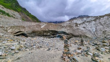 Stacked stones in front of the Shkhara Glacier in the Greater Caucasus Mountain Range in Georgia, Svaneti Region, Ushguli. Wanderlust, Stone cairns. Freedom. Glacier melting. Patara enguri river. clipart