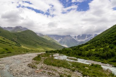 Patara Enguri Nehri Gürcistan 'ın Svaneti Bölgesi, Ushguli' deki Büyük Kafkasya Dağları 'ndaki bir vadiden aşağı akıyor. Shkhara Dağı bulutlarla kaplı. Karla kaplı dağlar. Buzul.