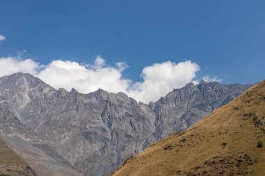 Gürcistan 'daki Büyük Kafkasya Dağları' ndaki Kuro sırtlarında panoramik bir manzara. Yüksek yamaçlar çorak ve taşlıdır. Aşağıdaki yemyeşil otlaklar. Açık ve parlak bir gün. Stepantsminda.Macera