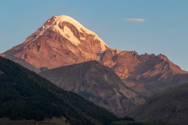 Gürcistan 'ın Büyük Kafkasya Dağları' ndaki Kazbegi Dağı 'nda panoramik bir sabah manzarası. Kar kaplı zirvenin üzerinde açık bir gökyüzü. Khokh menzili. Gün batımı, gün doğumu. Gizemli. Macera ve keşif