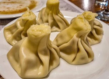 Geleneksel bir Gürcü hamur tatlısı olan Khinkali tabağına yakından bakmak. Ulusal Gürcü mutfağı. Üst Manzara. Sokak yemeği. Buharda pişmiş börek. Tiflis. Hamur torbasına sarılmış et.