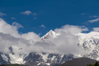 Svaneti Bölgesi 'nin Gürcistan' daki Ushguli köyü yakınlarındaki Shkhara Buzulu 'nun Chubedishi bakış açısından inanılmaz bir manzara. Karla kaplı dağlar bulutlarla kaplı..