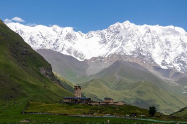 Gürcistan, Svaneti Bölgesi 'ndeki Büyük Kafkasya Dağları' nda, karlı Shkhara zirvesi yakınlarındaki Ushguli dağ köyündeki Lamaria kilisesinin muhteşem manzarası. Shkhara Buzulu 'na bak.