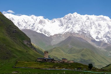 Amazing view on the Lamaria church in the mountain village Ushguli, near the snowy Shkhara peak in the Greater Caucasus Mountain Range in Georgia, Svaneti Region. View on the Shkhara Glacier. clipart