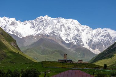 Gürcistan, Svaneti Bölgesi 'ndeki Büyük Kafkasya Dağları' nda, karlı Shkhara zirvesi yakınlarındaki Ushguli dağ köyündeki Lamaria kilisesinin muhteşem manzarası. Shkhara Buzulu 'na bak.