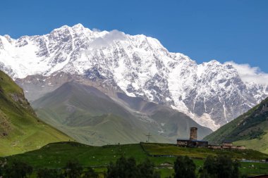 Gürcistan, Svaneti Bölgesi 'ndeki Büyük Kafkasya Dağları' nda, karlı Shkhara zirvesi yakınlarındaki Ushguli dağ köyündeki Lamaria kilisesinin muhteşem manzarası. Shkhara Buzulu 'na bak.