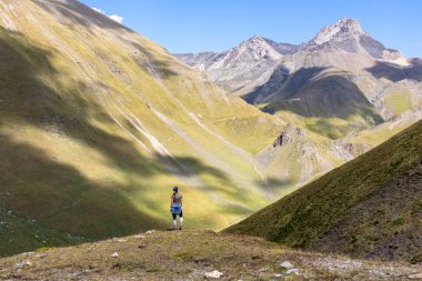 Gürcistan, Kazbegi Bölgesi 'ndeki Büyük Kafkasya Dağları' ndaki Chaukhi Geçidi 'ni oluşturan Chaukhi tepelerini izleyen bir kadın. Dişi sırt çantası sakinliğin tadını çıkarıyor. Koşun!