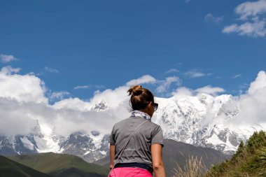 A female backpacker on a hiking trail to Chubedishi viewpoint. There is an amazing view on the Shkhara Glacier,near the village Ushguli the Greater Caucasus Mountain Range in Georgia, Svaneti Region clipart