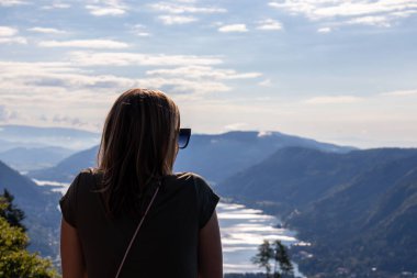 Avusturya Alpleri, Carinthia 'da Oswaldiberg Gölü manzaralı bir şapelin izleme platformunda duran bir kadın. Kadın panoramik manzarayı seviyor. Sabah havası, Özgürlük