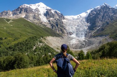 Gürcistan, Svaneti Bölgesi 'ndeki Büyük Kafkasya Dağları' ndaki Tetnuldi, Gistola, Lakutsia ve Adishi Buzulu 'nun panoramik manzarasının keyfini çıkaran bir kadın sırt çantası..