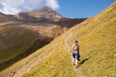 Gürcistan, Kazbegi 'deki Büyük Kafkasya Dağları' ndaki Chaukhi Geçidi 'nde panoramik manzaralı yürüyüş parkurunda bir kadın. Vadi yemyeşil. Seyahat tutkusu.