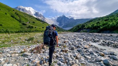 Gürcistan, Svaneti Bölgesi 'ndeki Büyük Kafkasya Dağları' ndaki Tetnuldi, Gistola ve Lakutsia 'nın panoramik manzarasının tadını çıkaran bir adam. Seyahat tutkusu, sırt çantası.