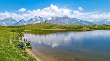 Koruldi Gölü 'nde atlayan bir adam, Gürcistan' ın Yukarı Svaneti bölgesindeki Büyük Kafkasya Dağları 'ndaki Mestia yakınlarındaki dağ sırtlarında inanılmaz bir manzarayla. Sudaki yansıma. Seyahat tutkusu.