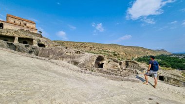 Doğu Avrupa 'nın Kafkasya, Gürcistan' ın Shida Kartli bölgesindeki Mtkvari nehrine bakan antik mağara kenti Uplistsikhe 'yi keşfeden bir erkek turist. Gezmek, turizm, yürümek. Gori yakınlarında.