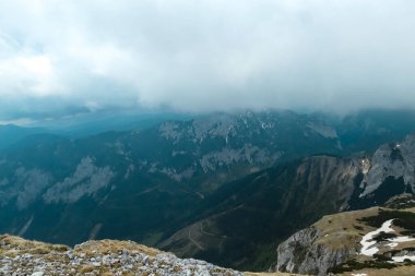 Avusturya 'nın Yukarı Styria bölgesindeki Hochschwab Bölgesi' nin bulut kaplı dağ zirvelerindeki dağlık bir çayırda manzaralı yürüyüş patikası. Alpler, Avrupa 'da yağmurlu bir bahar günü. Hava yüksek irtifada değişir. Rüzgâr