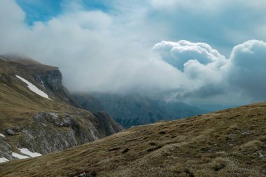 Avusturya 'nın Yukarı Styria bölgesindeki Hochschwab Bölgesi' nin bulut kaplı dağ zirvelerindeki dağlık bir çayırda manzaralı yürüyüş patikası. Alpler, Avrupa 'da yağmurlu bir bahar günü. Hava yüksek irtifada değişir. Rüzgâr