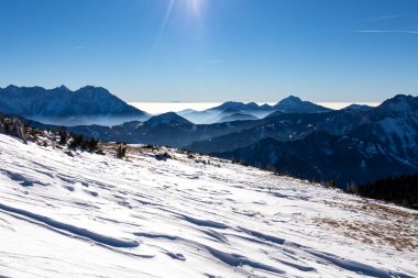 Avusturya, Carinthia 'daki Karawanks dağlarının karla kaplı tepelerinde panoramik manzara. Julian Alps. Avusturya Alpleri, Avrupa 'da kış harikalar diyarı. Kayak turu, kar ayakkabısı yürüyüşü. Hochobir. Mavi sisli tepeler.