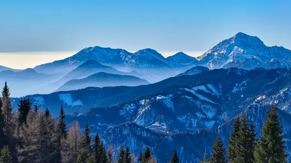 Avusturya, Carinthia 'daki Karawanks dağlarının karla kaplı tepelerinde panoramik manzara. Julian Alps. Avusturya Alpleri, Avrupa 'da kış harikalar diyarı. Kayak turu, kar ayakkabısı yürüyüşü. Hochobir. Mavi sisli tepeler.