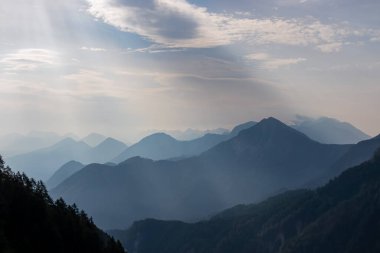 Avusturya, Carinthia 'daki Karawanklar' ın dağlık dağ zincirlerinin manzarası. Zirveler sabah sisiyle örtülüdür. Mistik titreşimler. Açık ve güneşli bir gün. Huzur. Görüntü: Ferlacher Spitze, Alpler