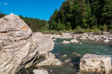 Villach, Carinthia, Avusturya 'daki Dobratsch doğal parkında akan Gail Nehri. Gailtaler ve Alpler. Riverbank kocaman kayalarla dolu. Kristal berrak suda yüzmek